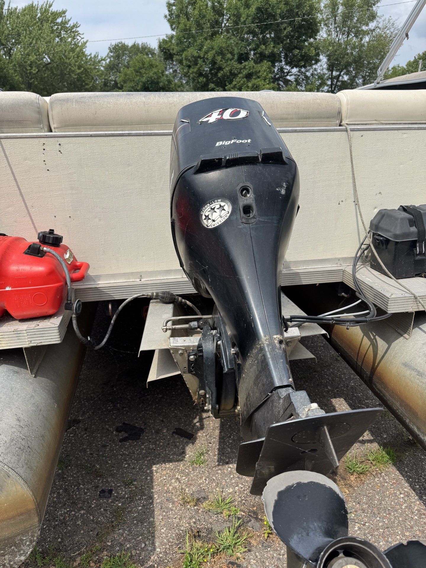 Rear view of a black outboard motor mounted on a small boat beside red fuel cans.