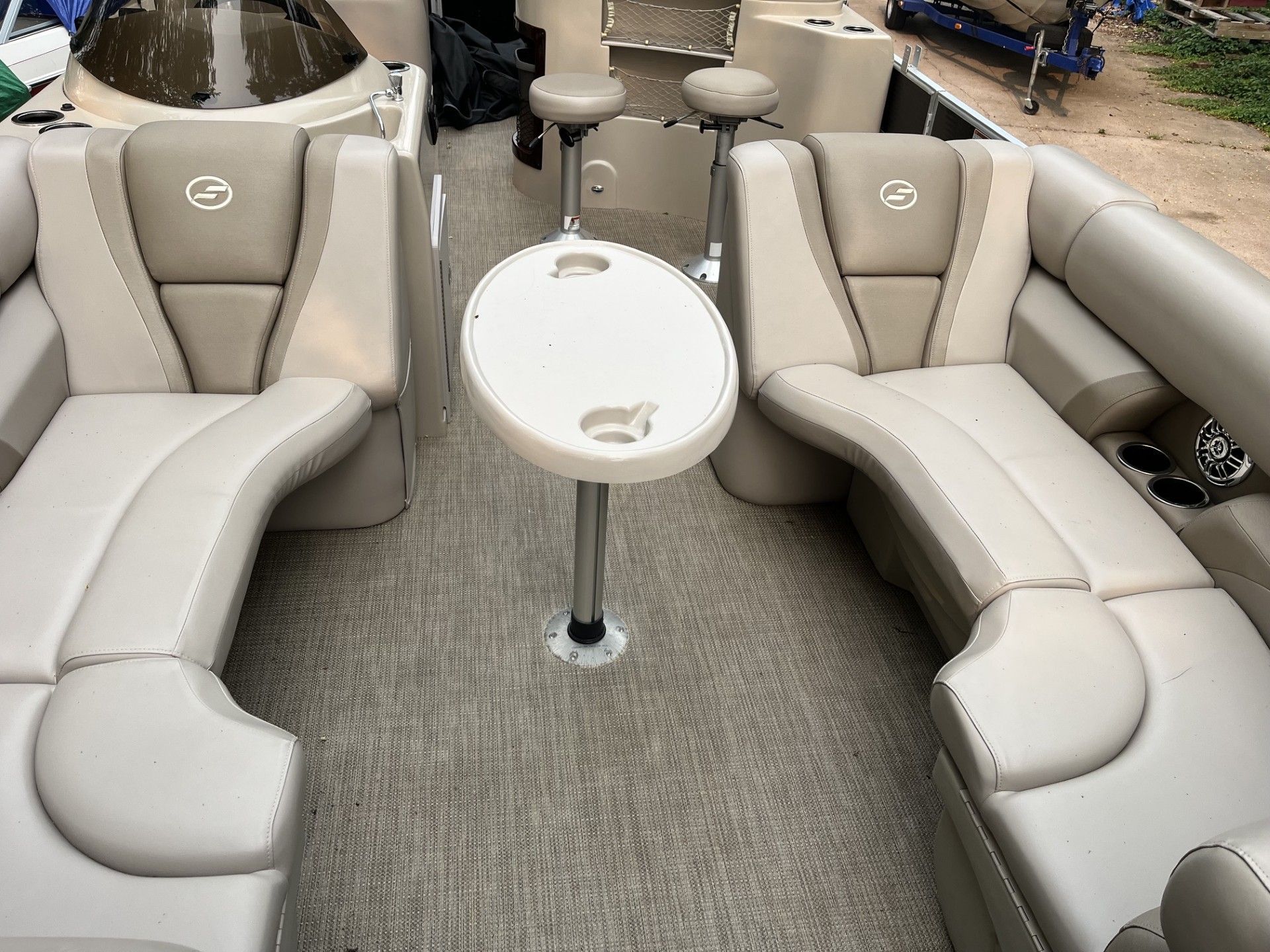 Boat cockpit with gray cushioned bench seating and a white round table on carpeted flooring