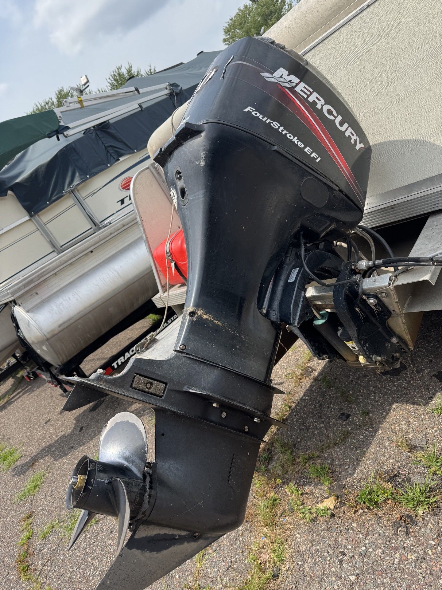 black Mercury outboard motor attached to a boat trailer on gravel.