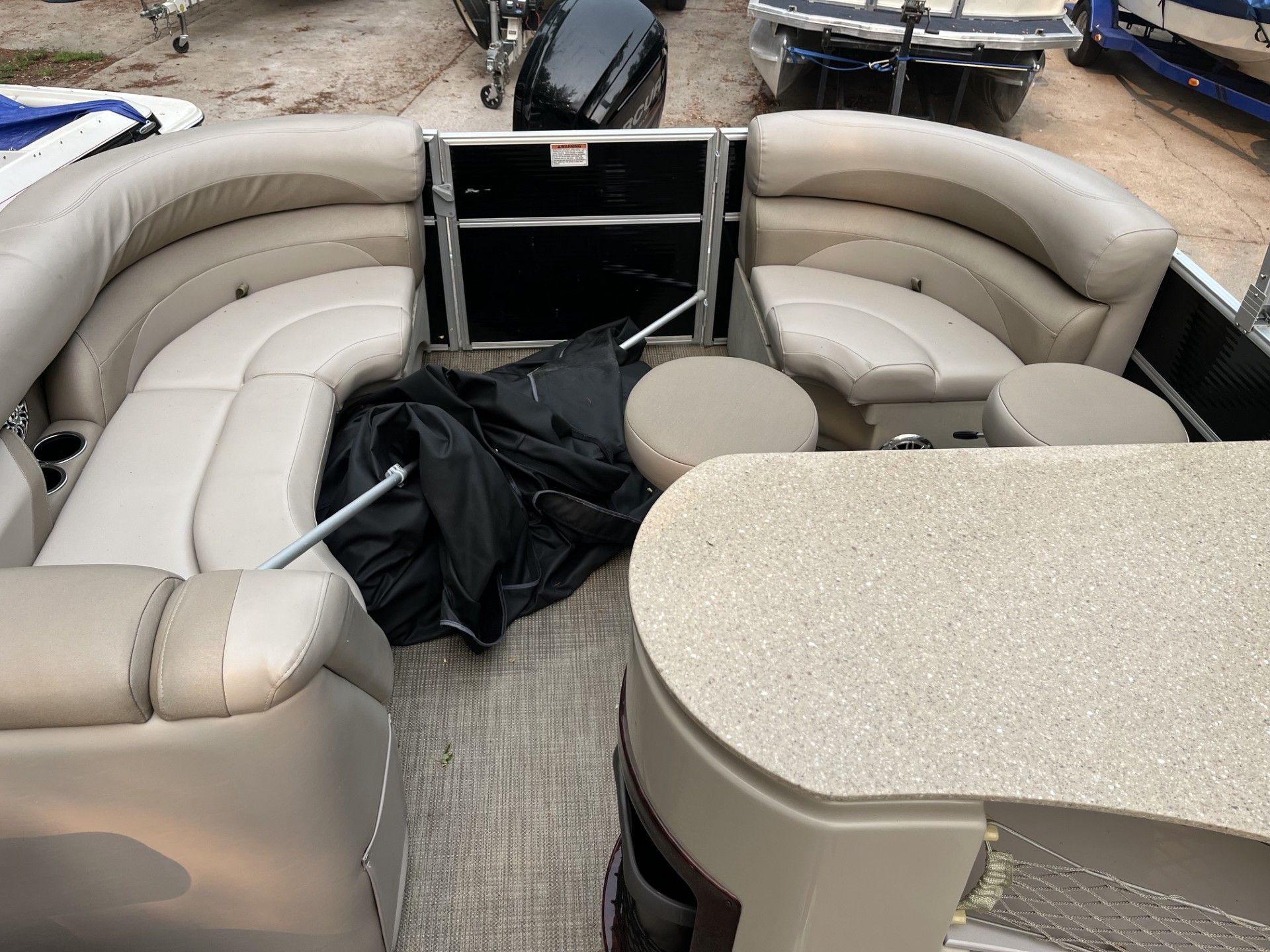 Starcraft 236 Party Lounger boat seating area with curved benches, table, and a black bag on the floor