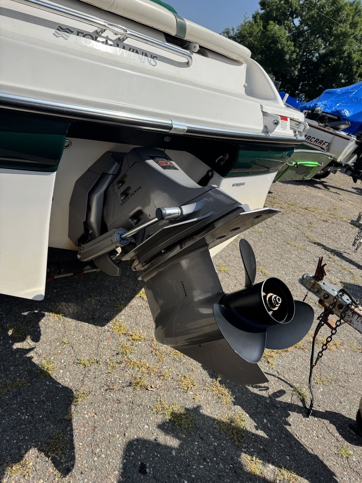 Close-up of a boat’s outboard motor and propeller at a dockside, with a blue sky in the background