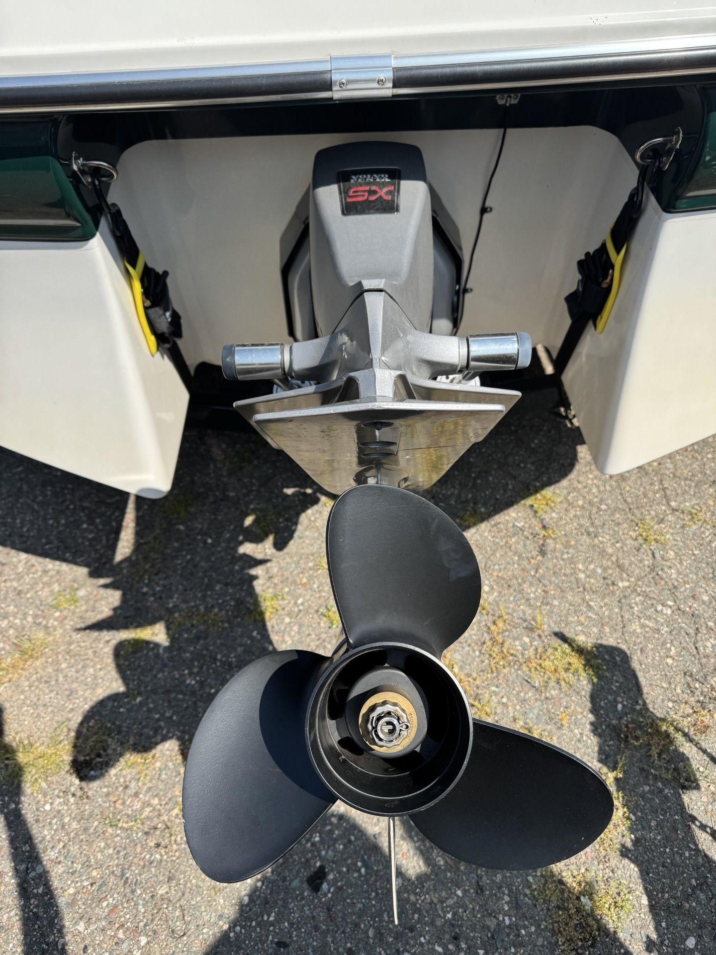 Boat stern with outboard motor and propeller, viewed from the rear on pavement