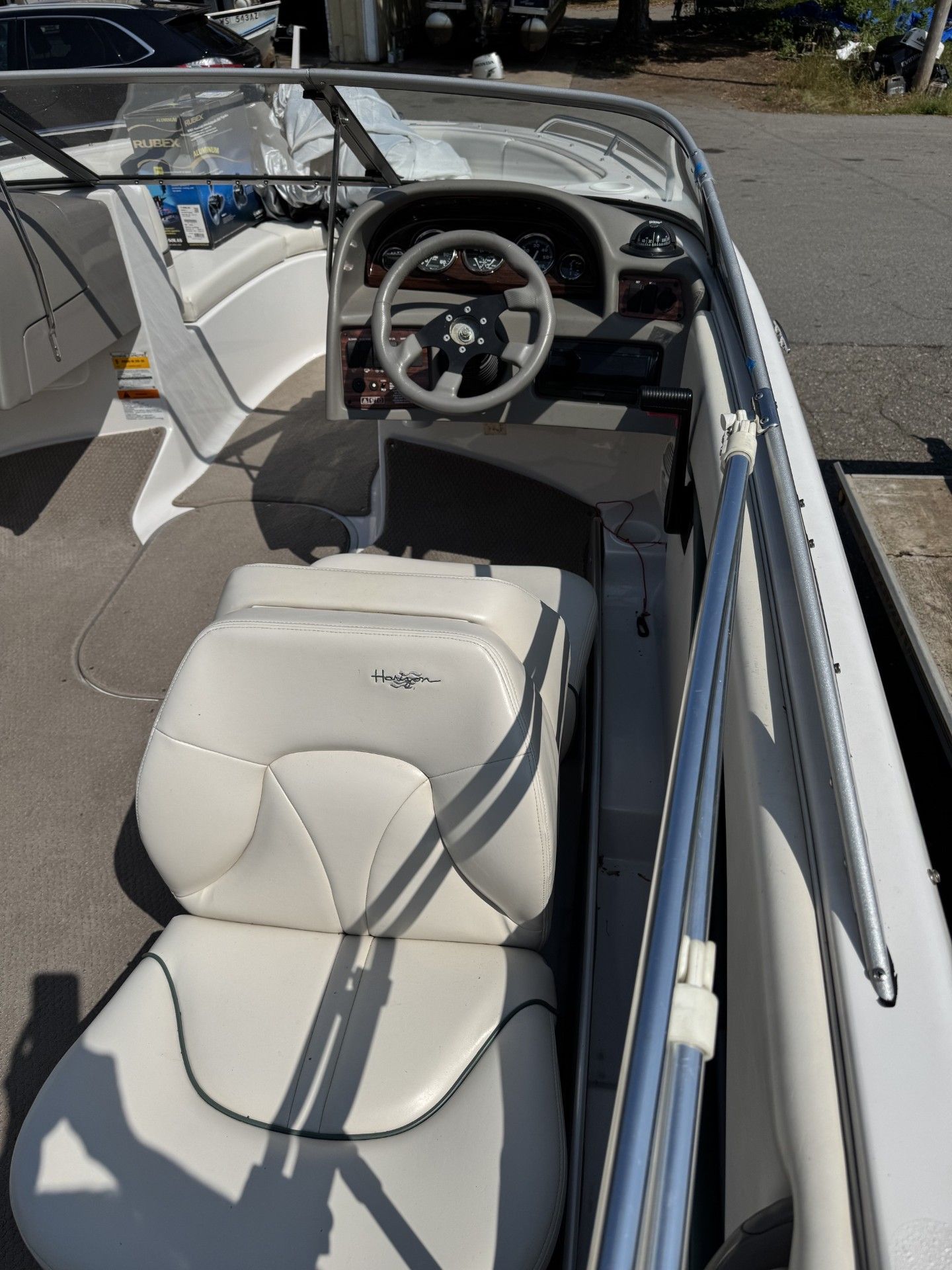 White leather boat seats and steering wheel in an open motorboat docked on a sunny day