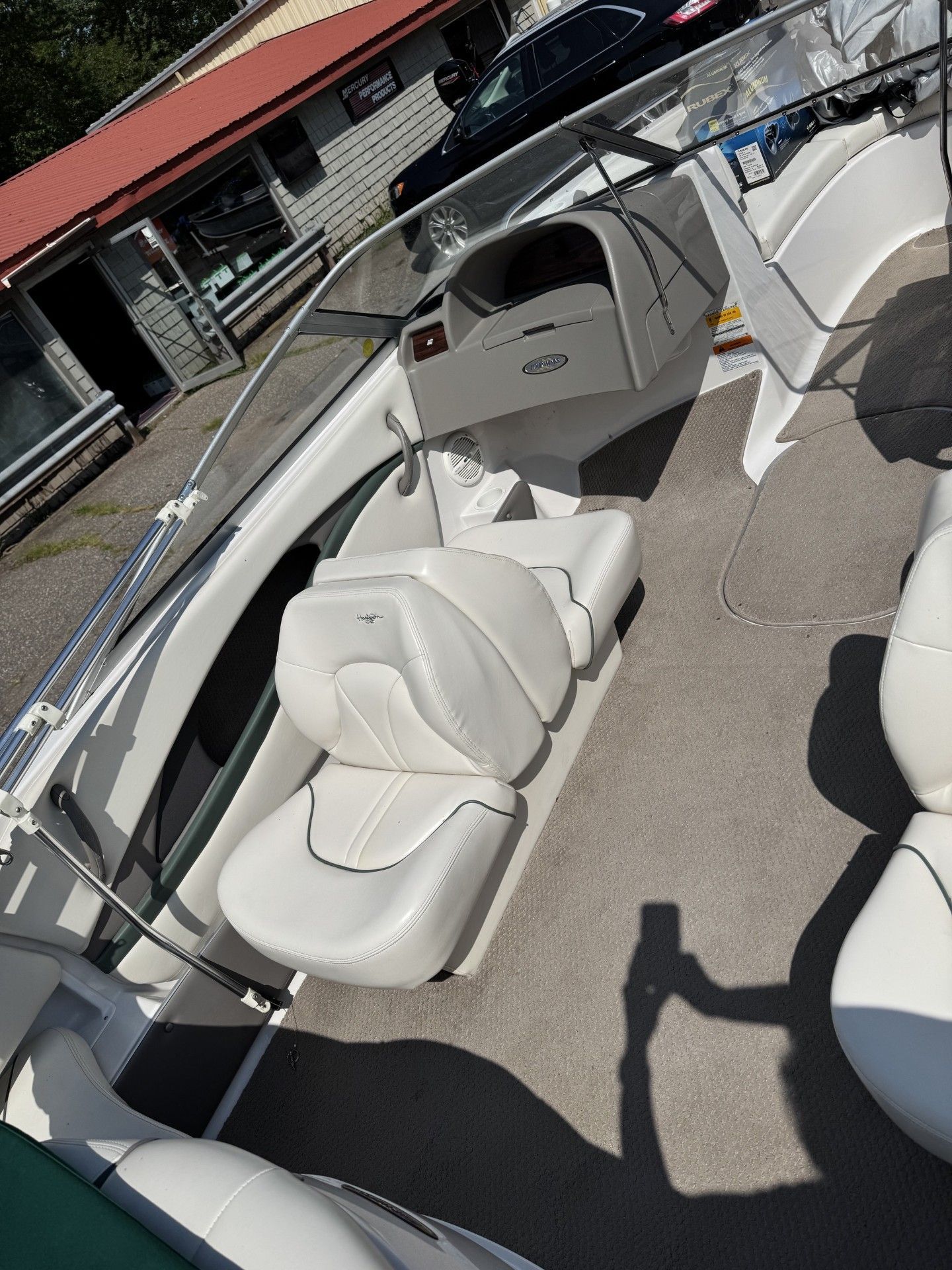 White pontoon boat interior with gray carpet and beige seats on a dockside marina