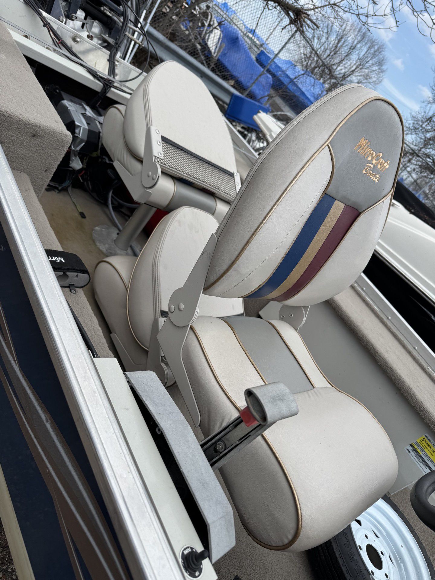 Light gray boat captain’s chair with blue and red stripe in a marina setting