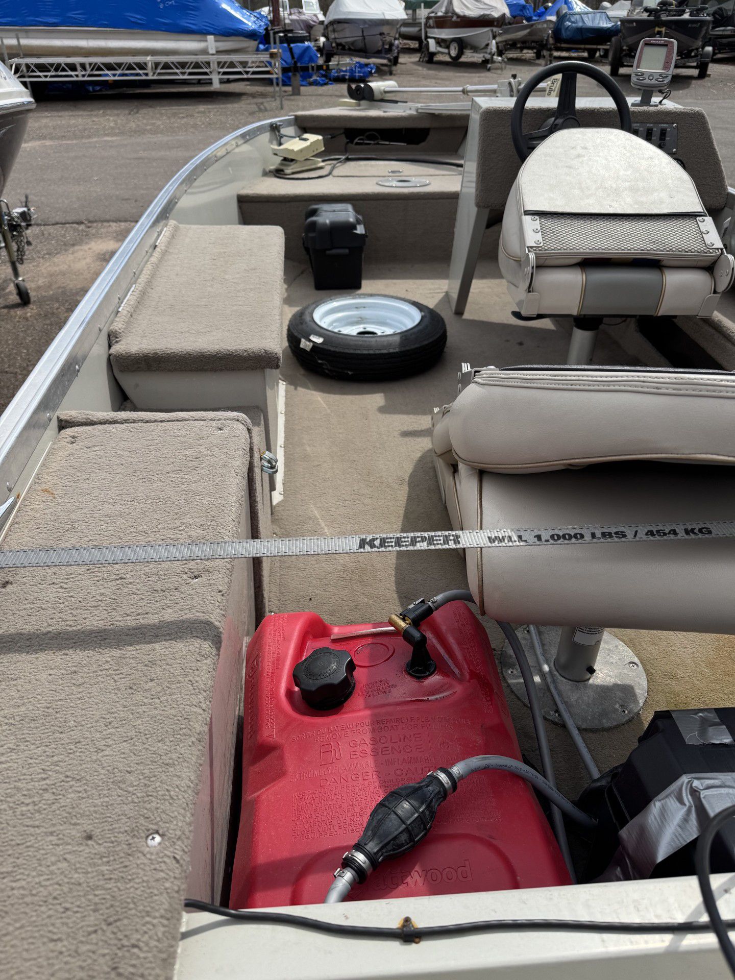Small beige fishing boat deck with seats, a red fuel tank, and a robotic vacuum cleaner on board.