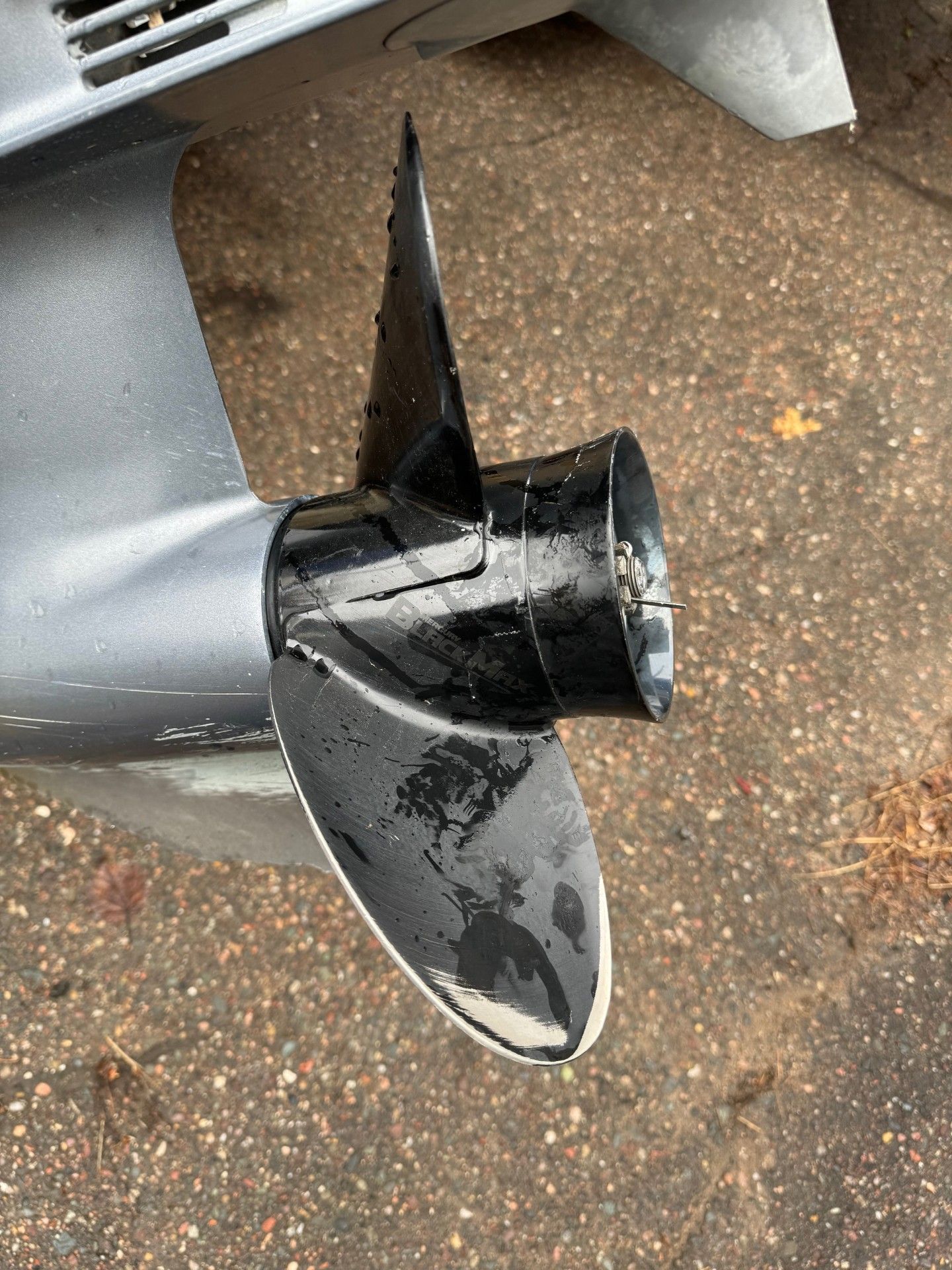 A close up of a boat propeller on the ground.