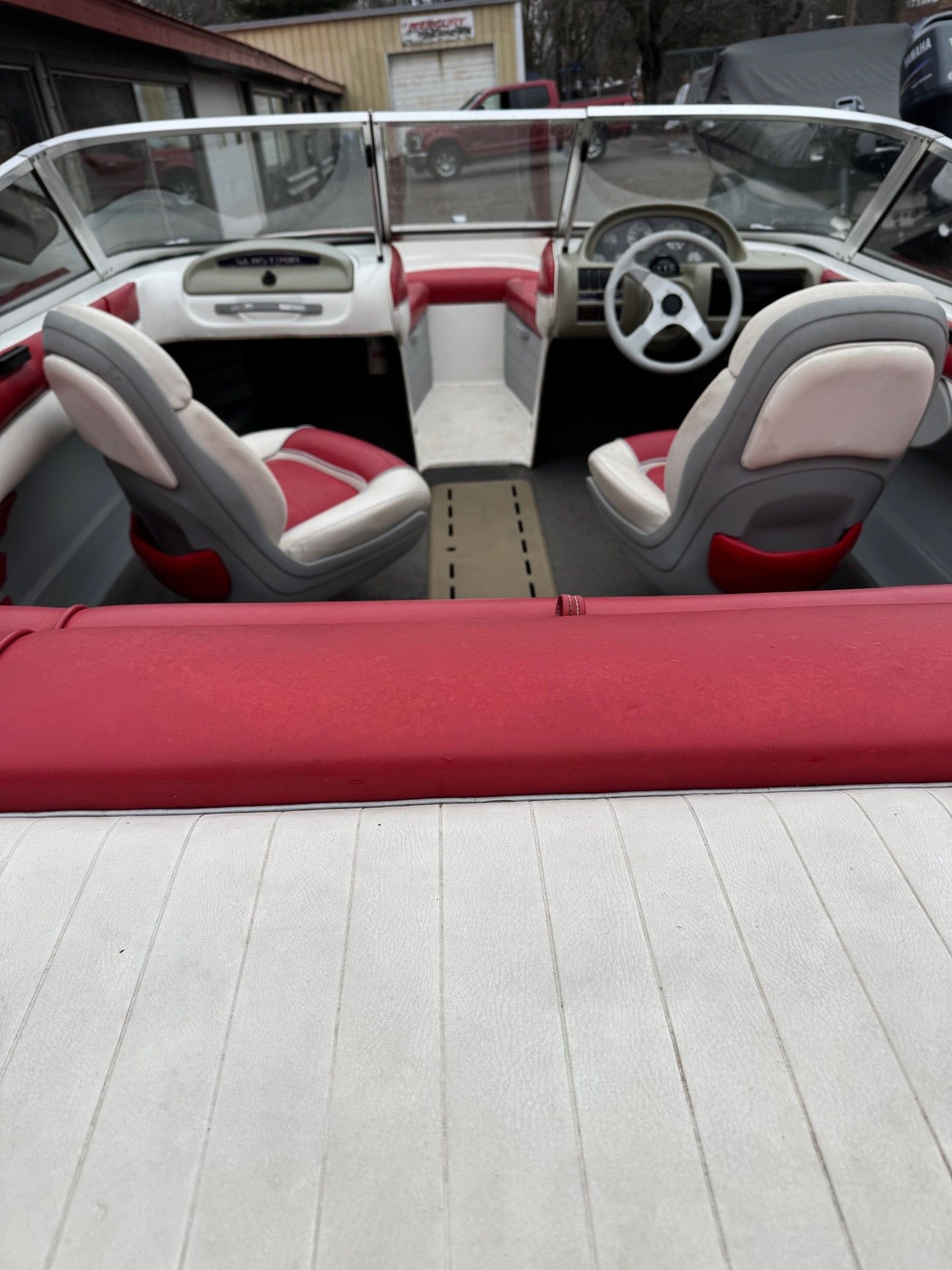 The inside of a boat with red seats and a steering wheel