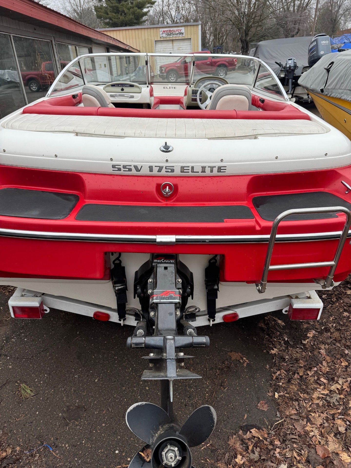 A red and white boat is parked in a parking lot.