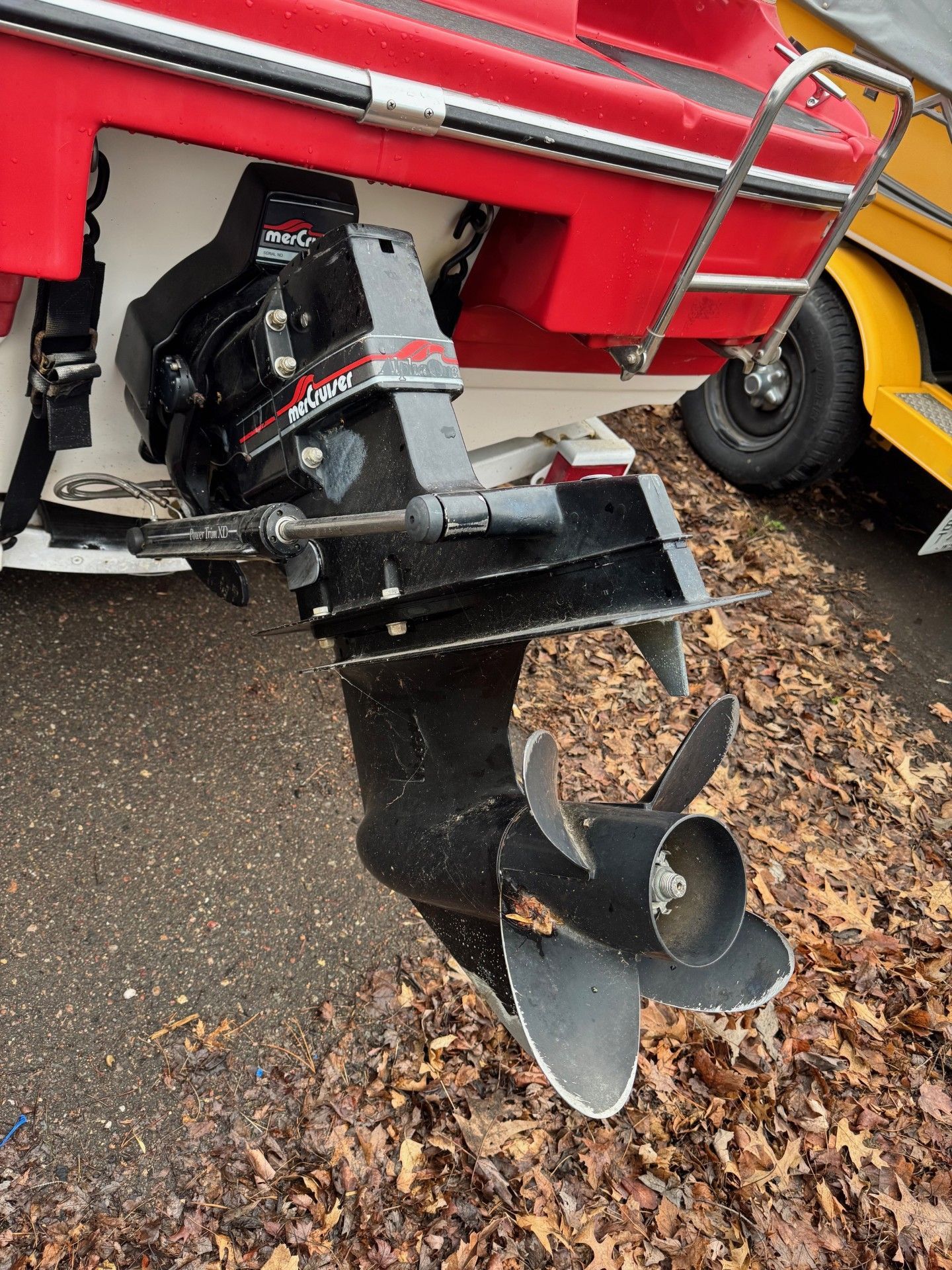 A red boat with a black outboard motor is parked on the side of the road.