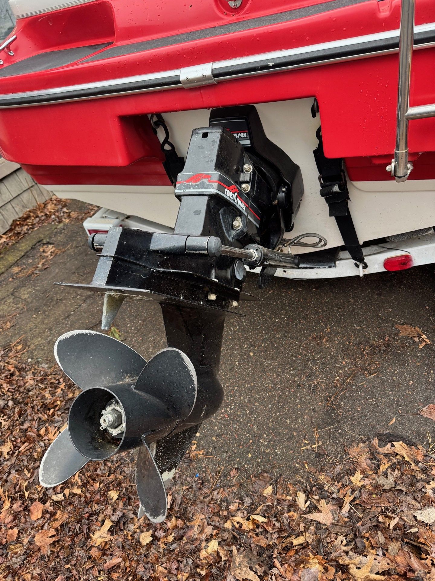 A red boat with a black outboard motor is parked on the side of the road.