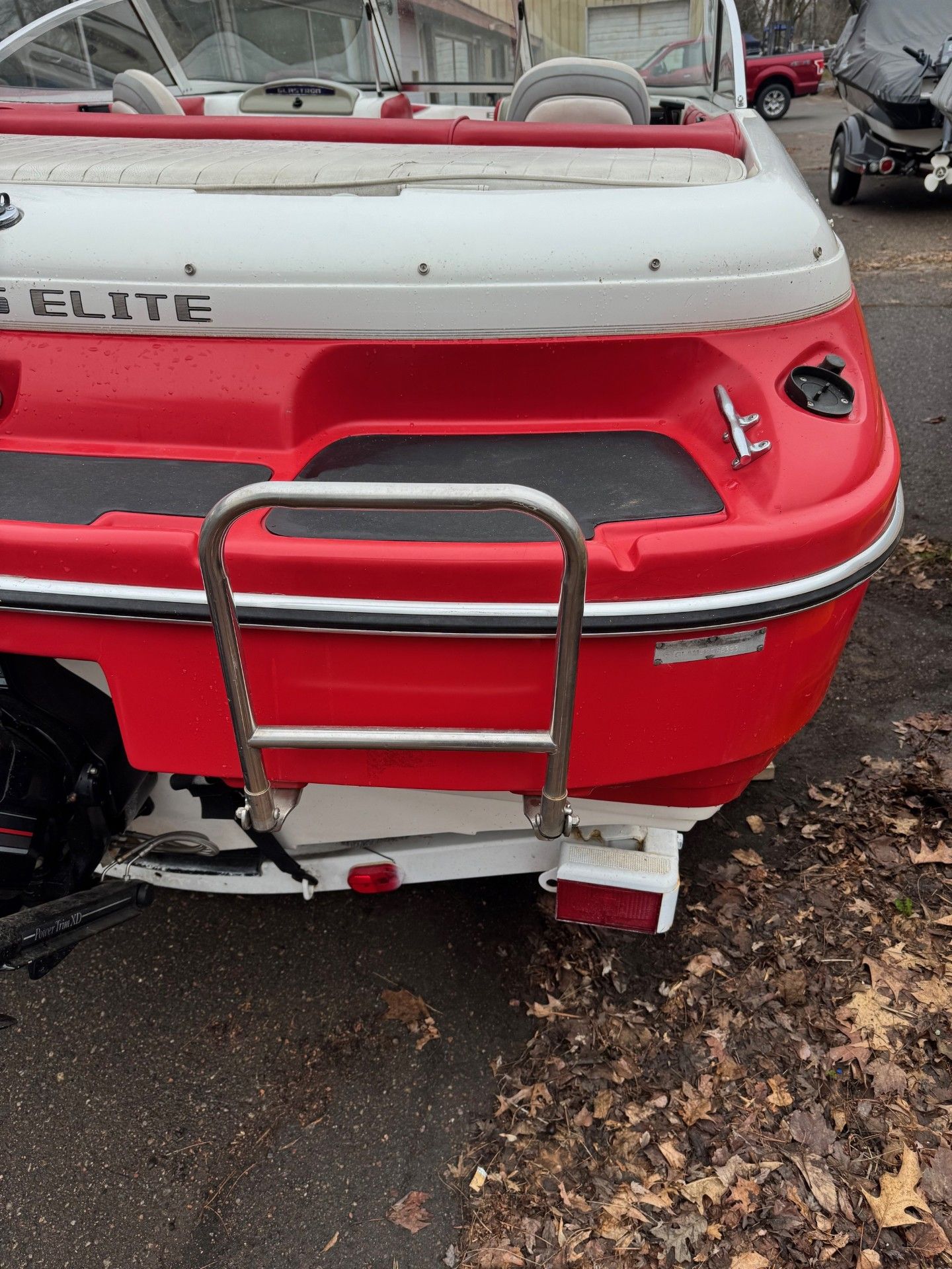 A red and white boat is parked on the side of the road.