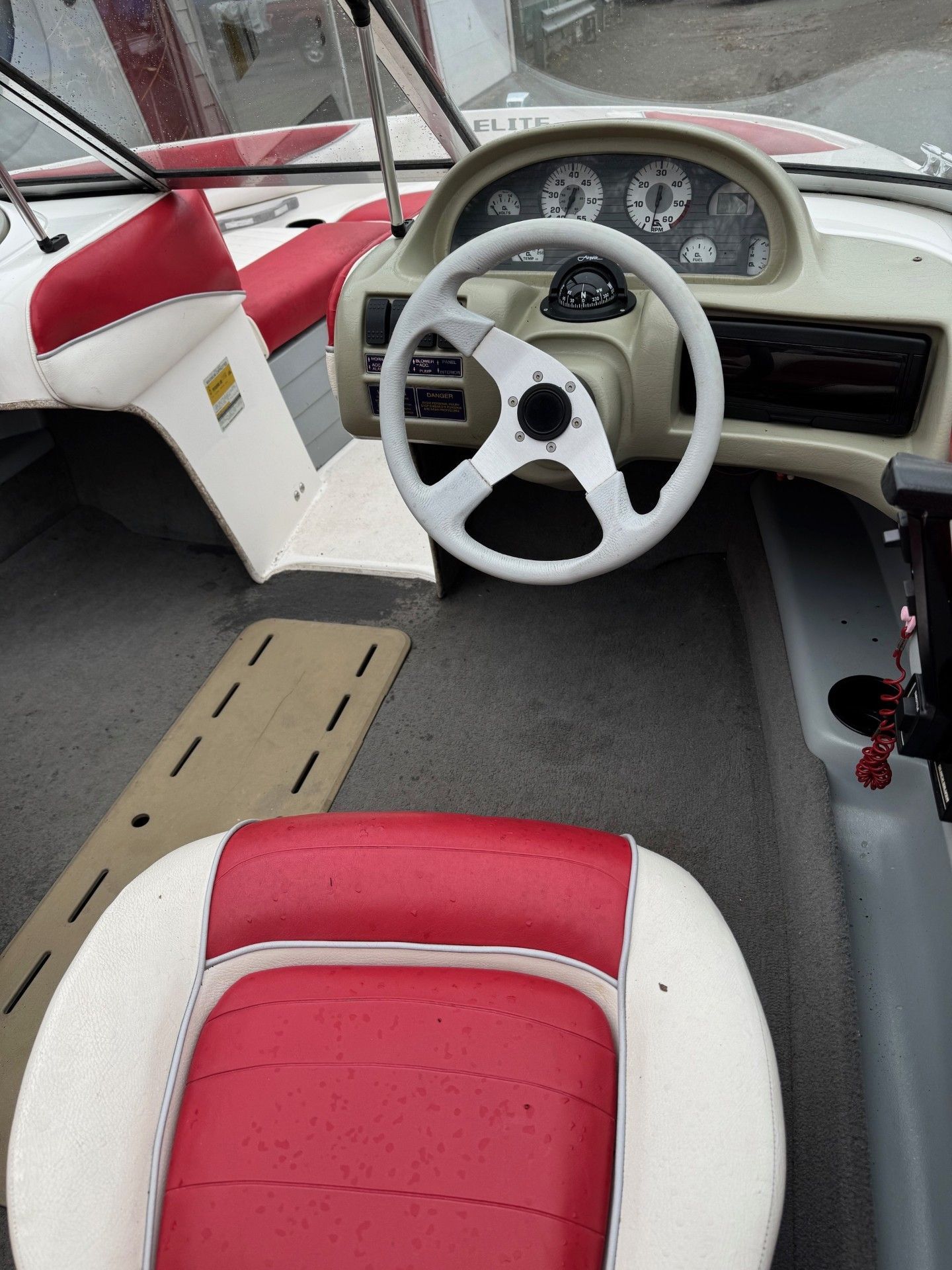 A boat with red and white seats and a steering wheel