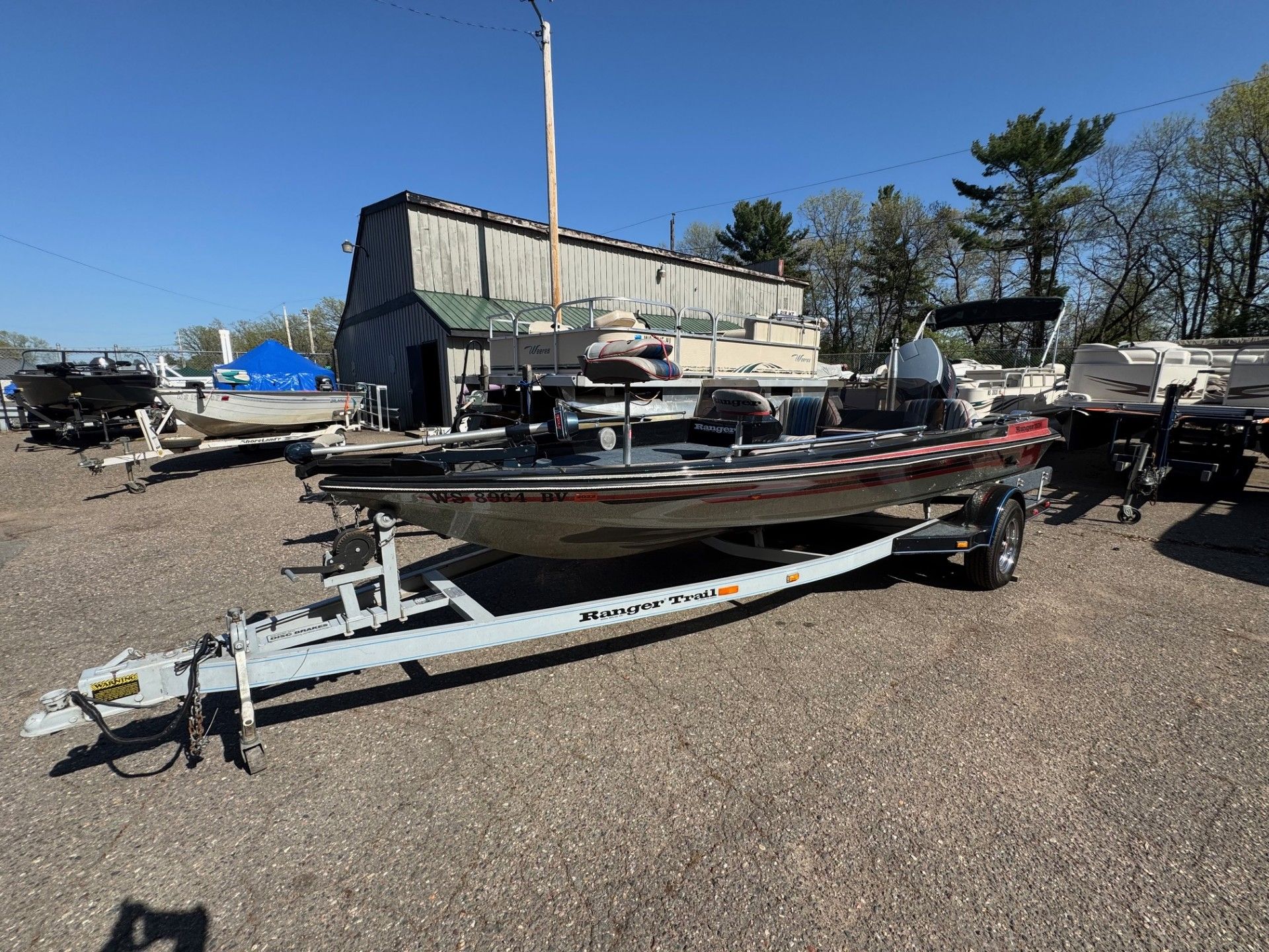 A boat is sitting on a trailer in a parking lot.