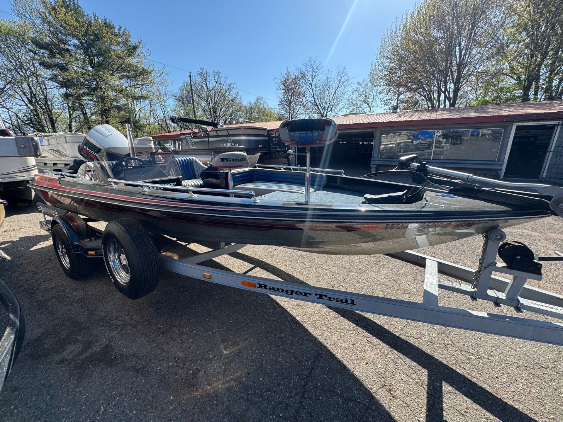 A fishing boat is parked on a trailer in a parking lot.
