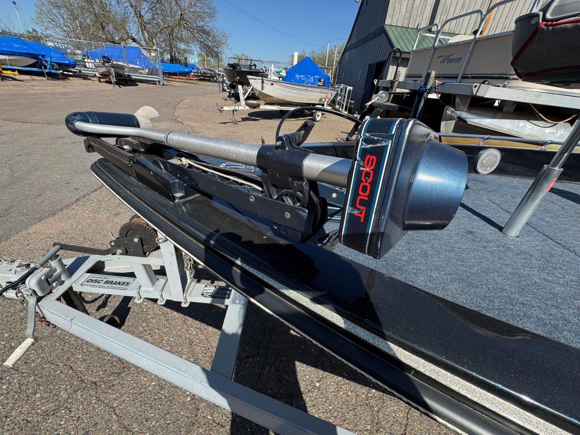 A boat with a motor attached to it is parked in a parking lot.
