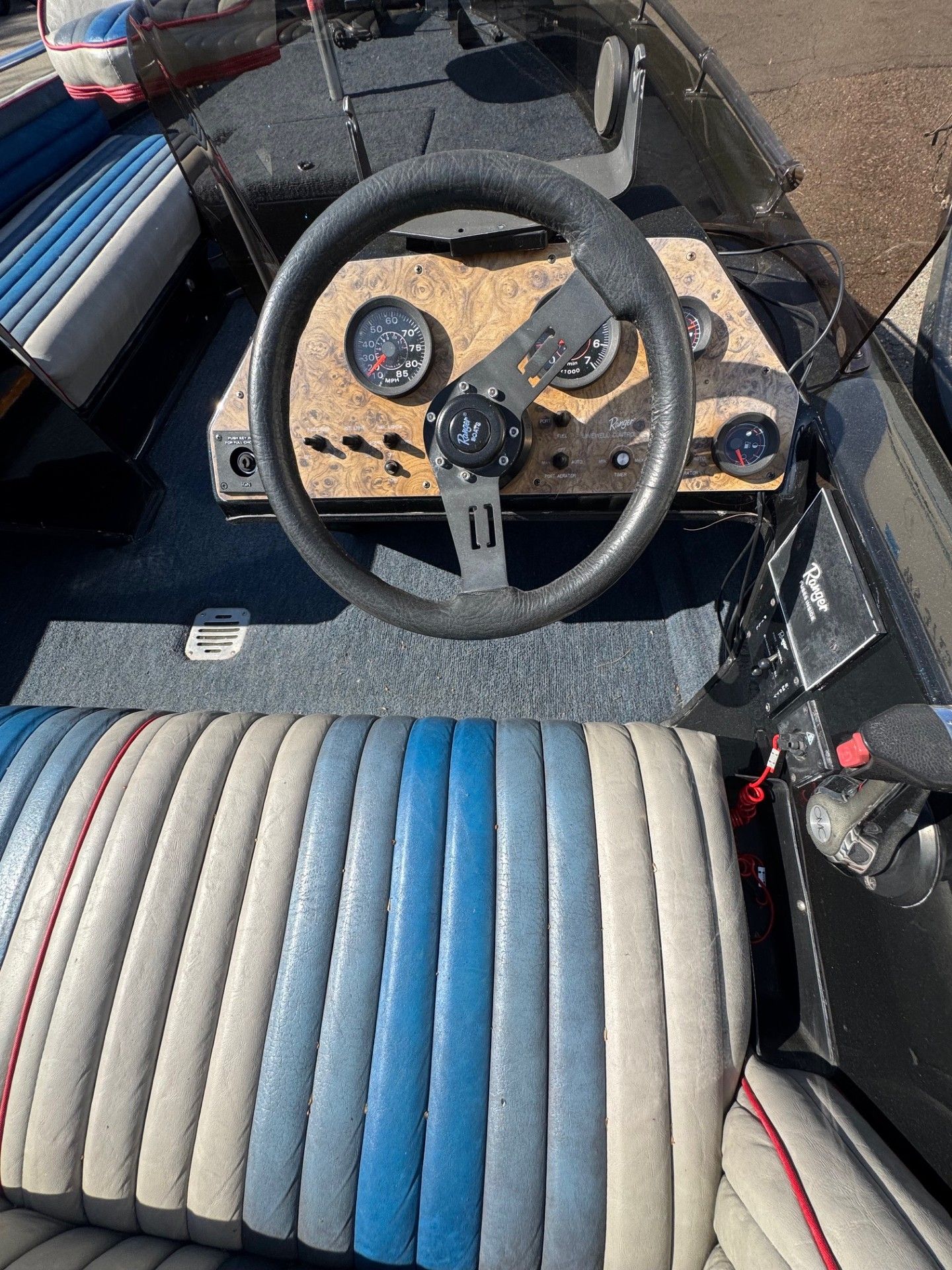 A boat with a steering wheel and a striped seat.