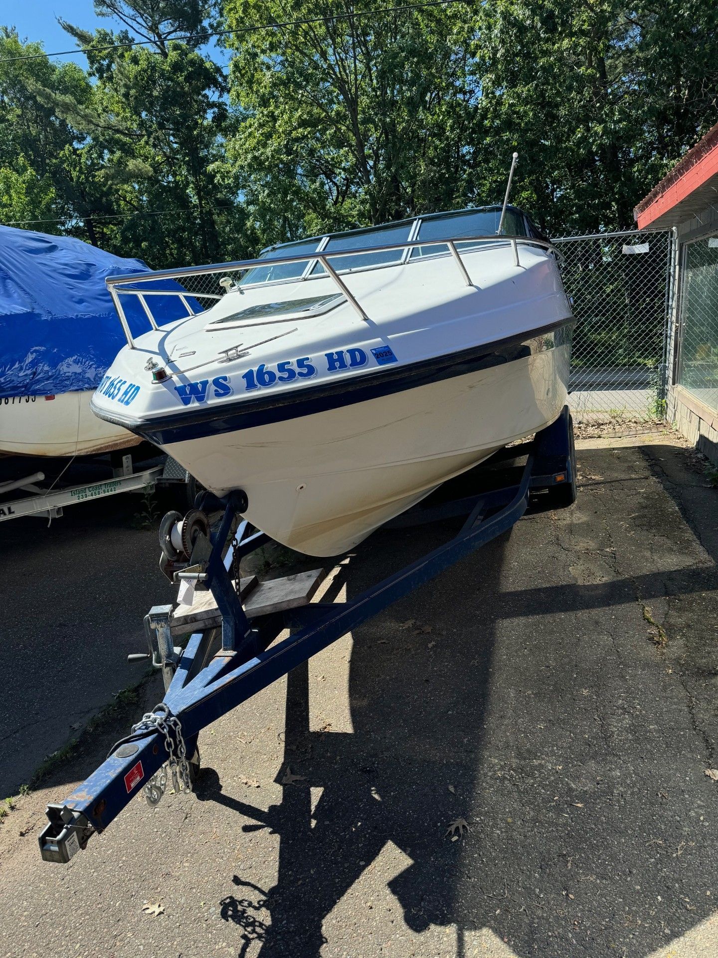 A boat is sitting on a trailer next to a fence