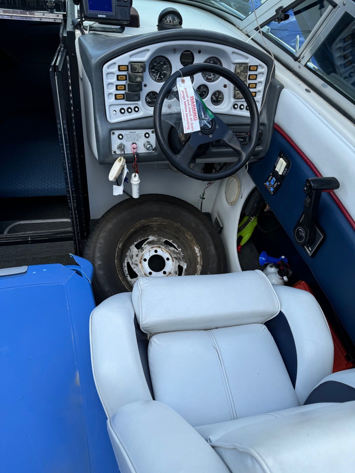 A boat with a steering wheel and a tire on the floor