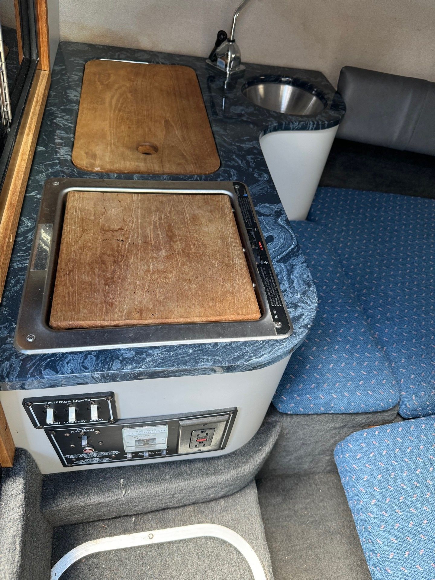 A kitchen with a sink and a covered stove on a boat