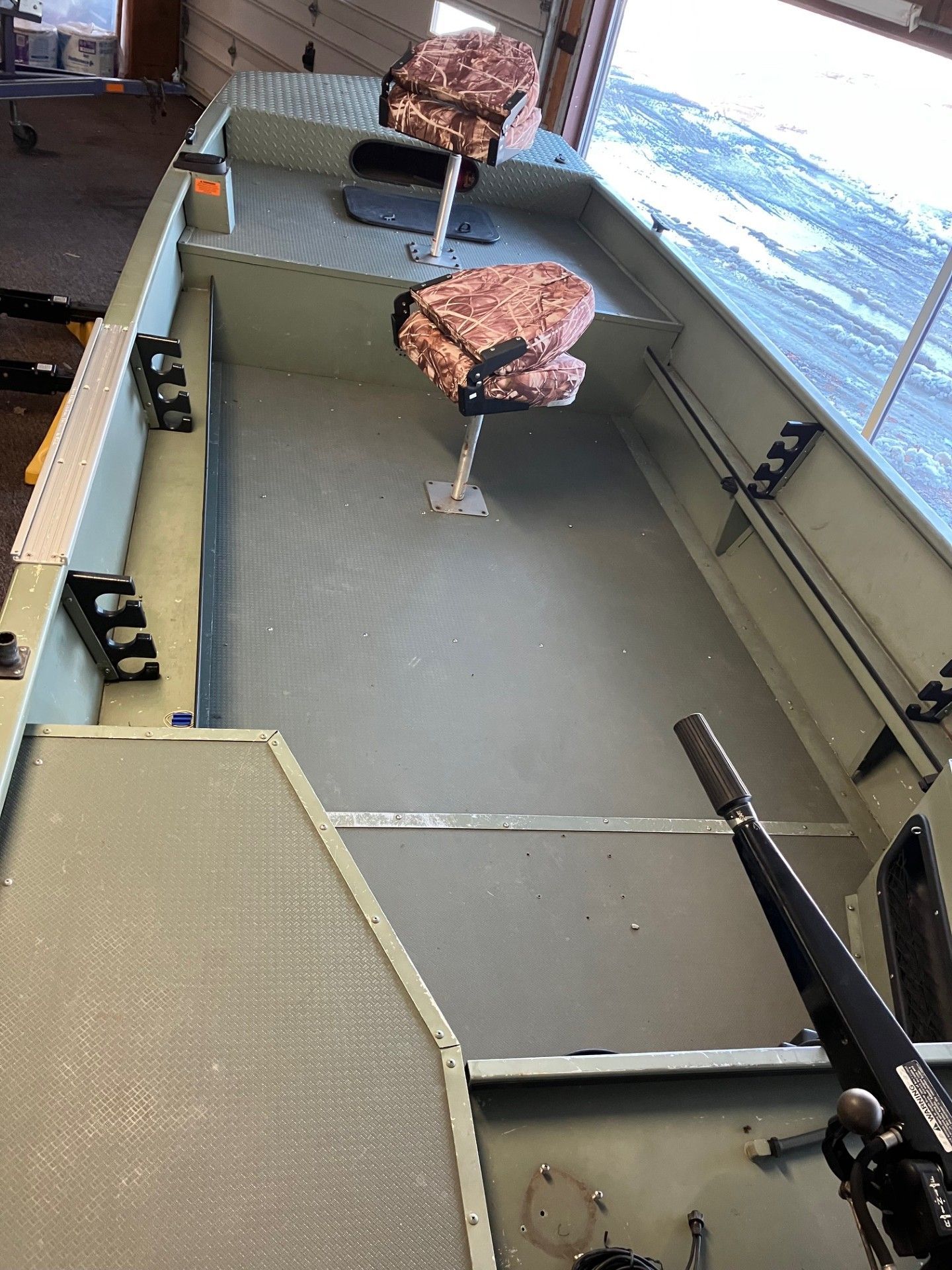 Empty, light green aluminum fishing boat interior with two swivel seats.