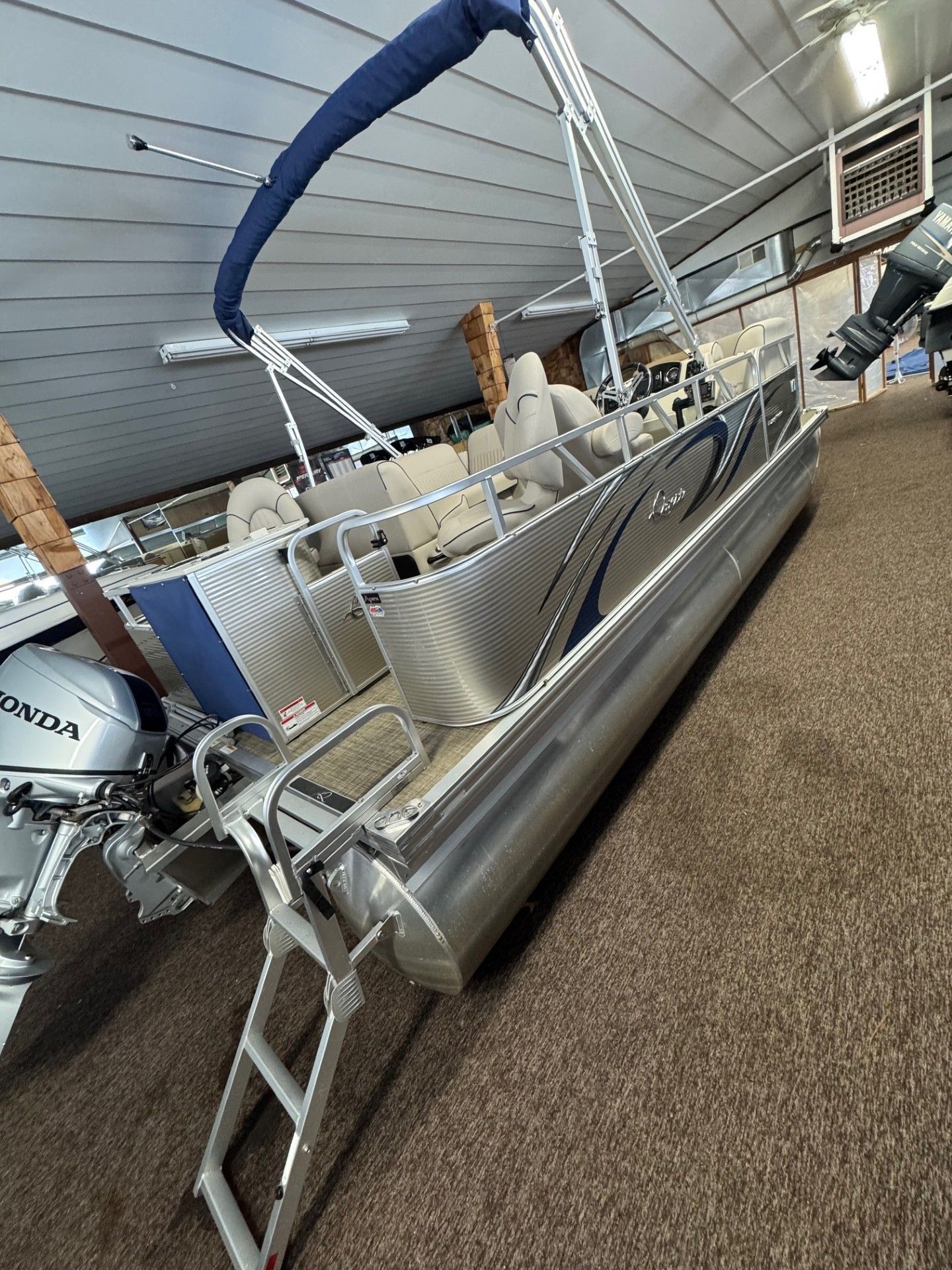 A pontoon boat with a ladder attached to it is sitting in a showroom.