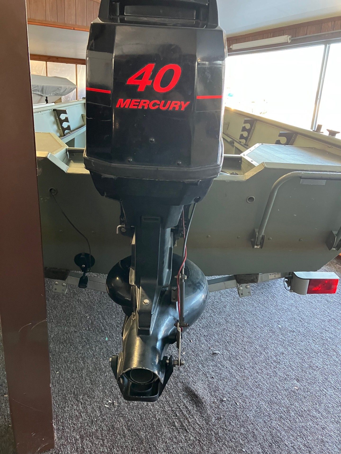 A black Mercury 40 outboard motor mounted on a green boat, in a marine setting.