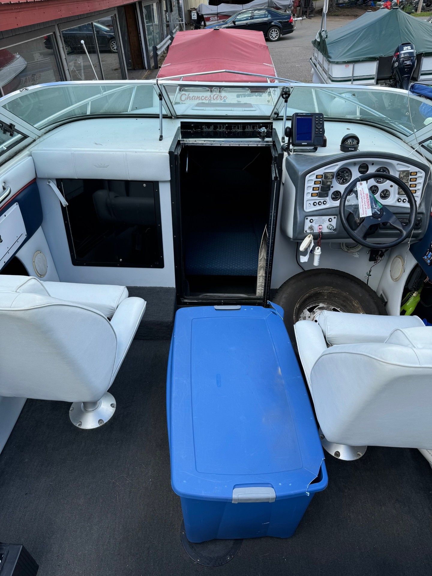 The inside of a boat with a blue cooler and chairs