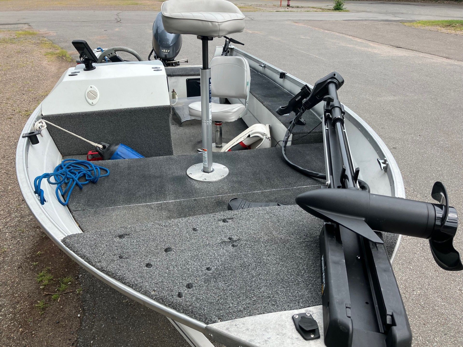 A small fishing boat with a trolling motor and mounted seats. Gray and white tones dominate the interior.