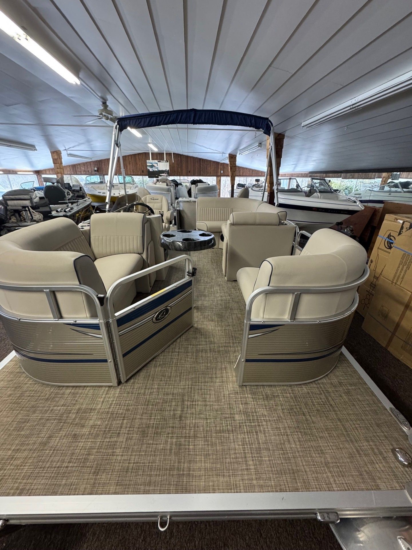 The inside of a pontoon boat is shown in a showroom.