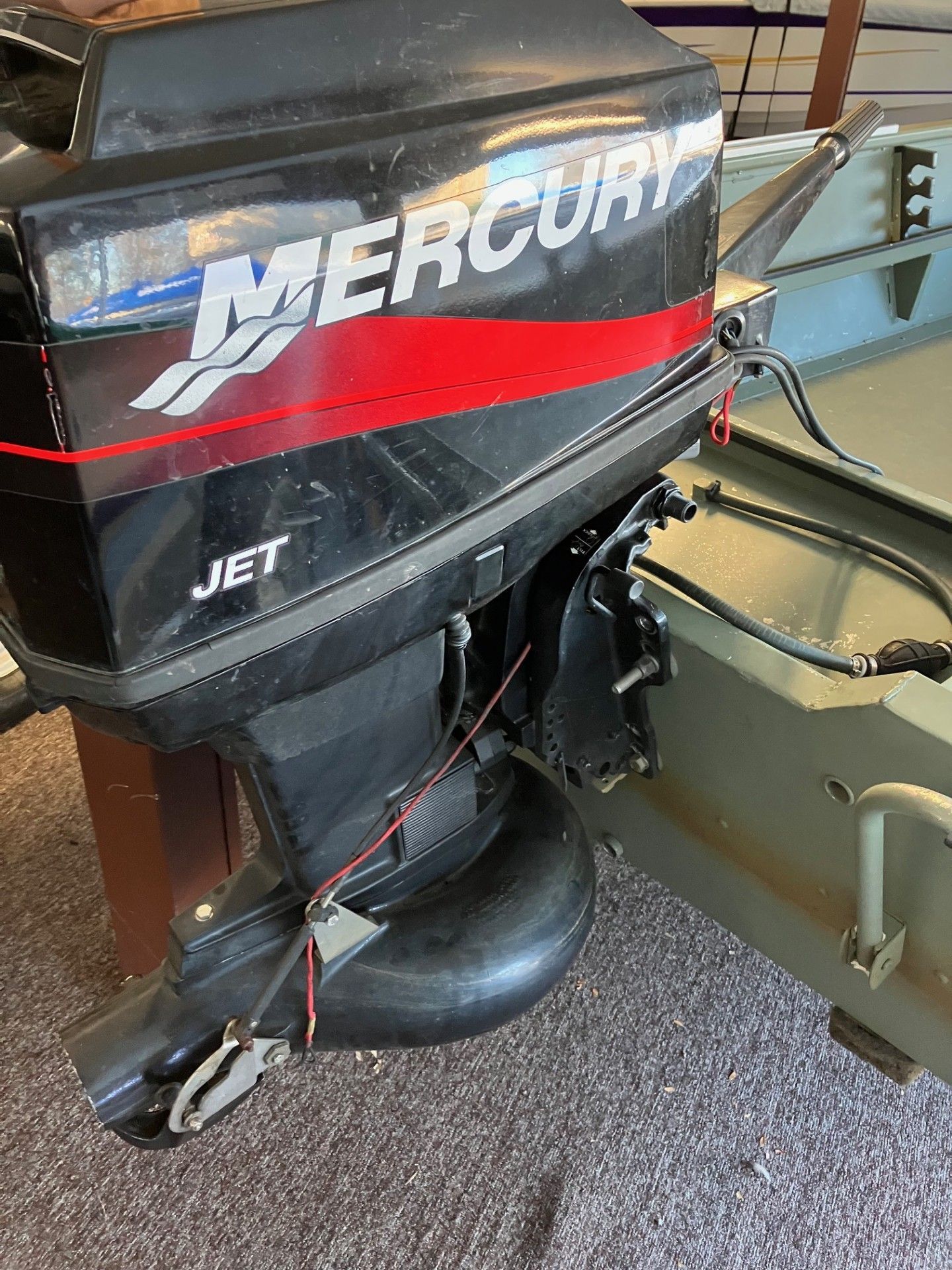 Black Mercury jet outboard motor on an olive green boat.