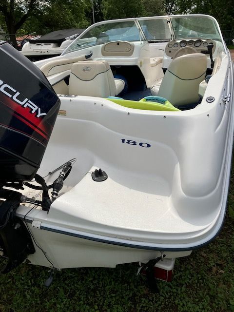 A white boat with a mercury engine is parked in the grass