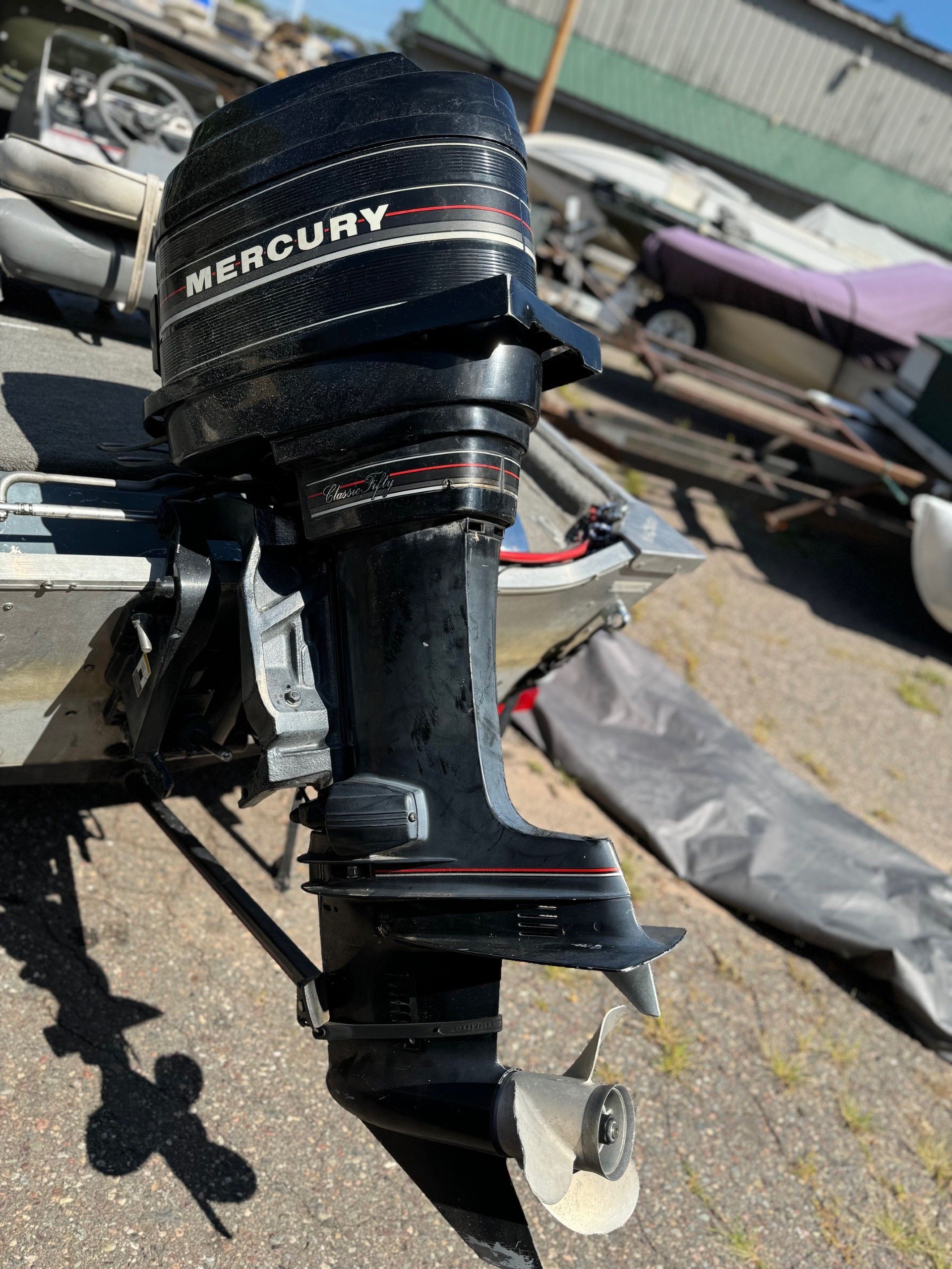 A mercury outboard motor is sitting on the ground next to a boat.