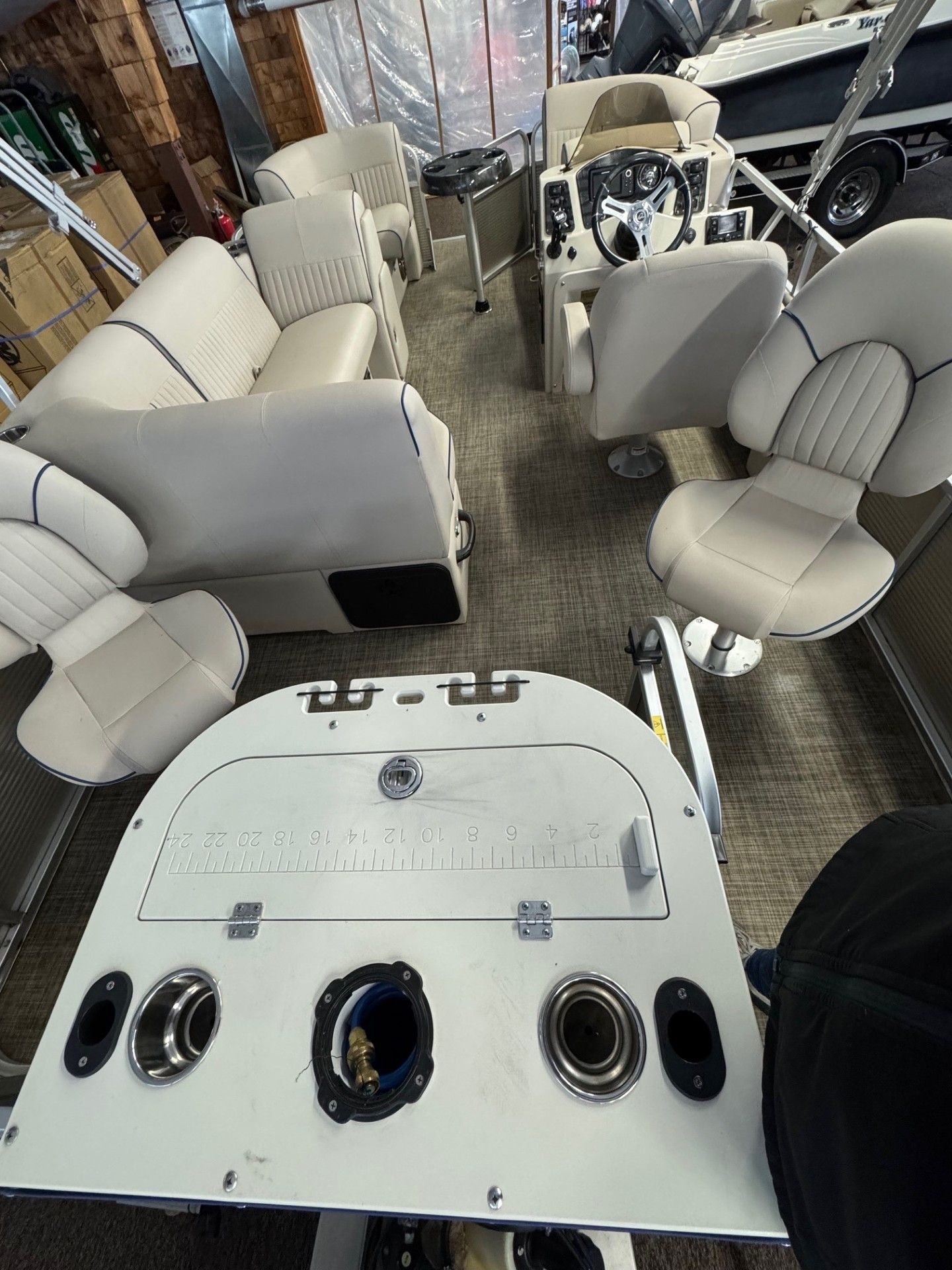 The inside of a pontoon boat with white seats and a steering wheel.