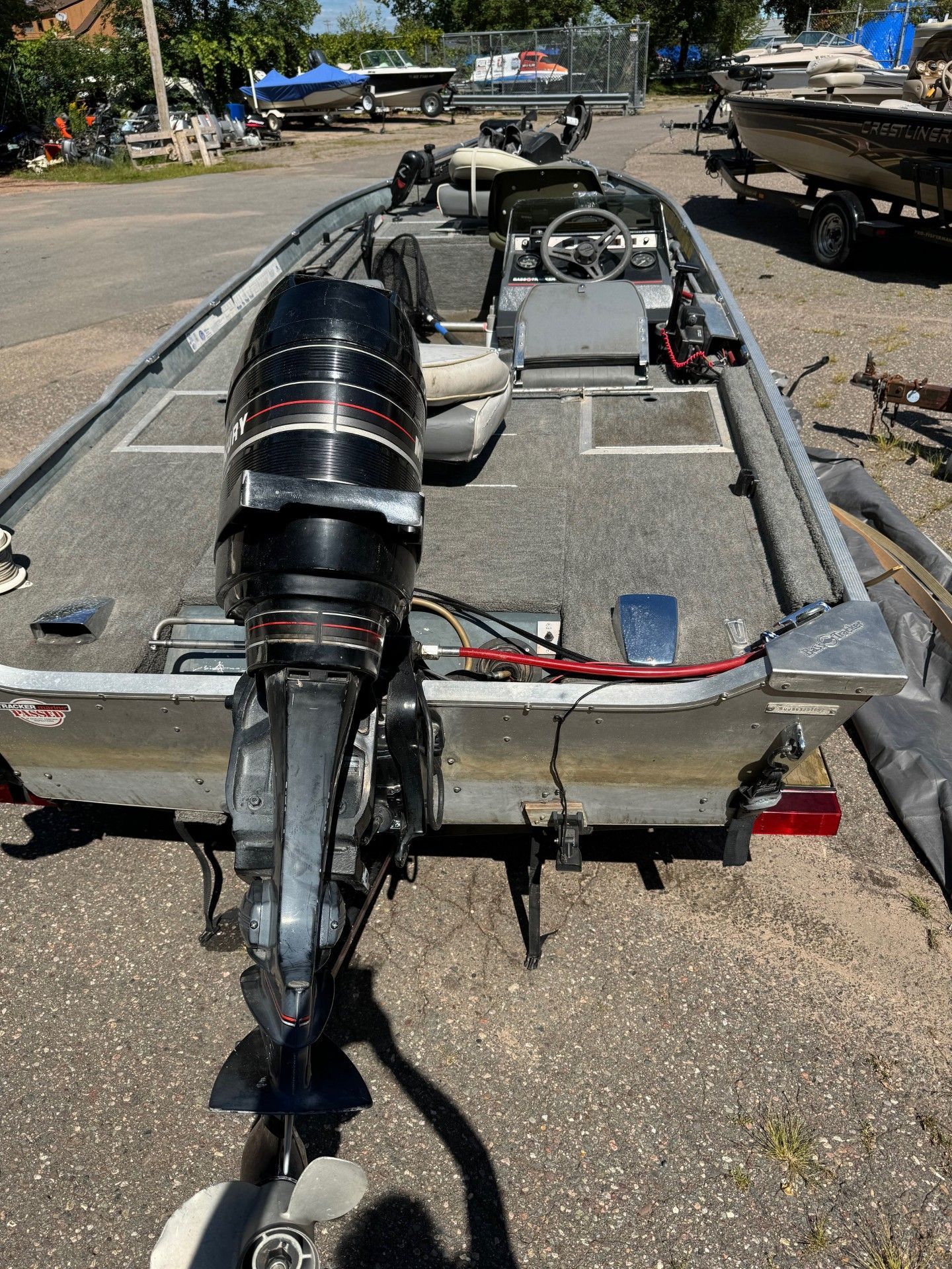 A fishing boat with a mercury outboard motor is parked on the side of the road.