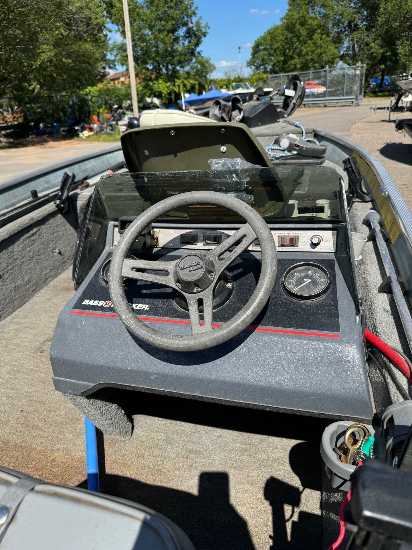 A boat with a steering wheel is parked on the side of the road.