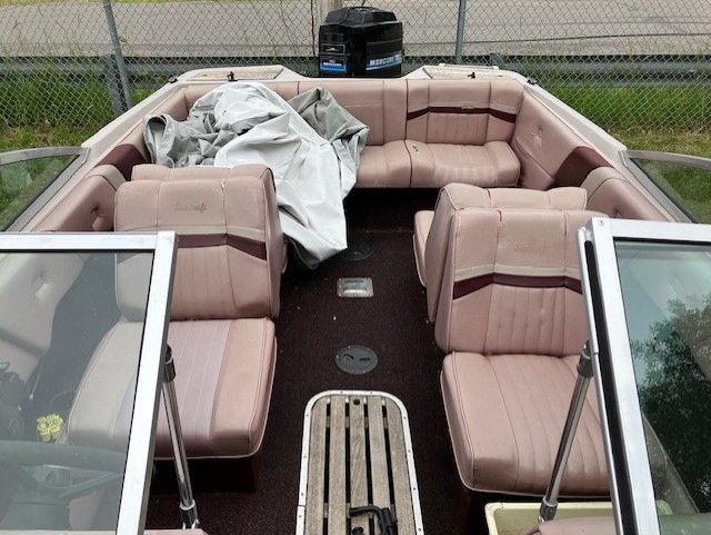 The inside of a boat with pink seats and a mercury motor