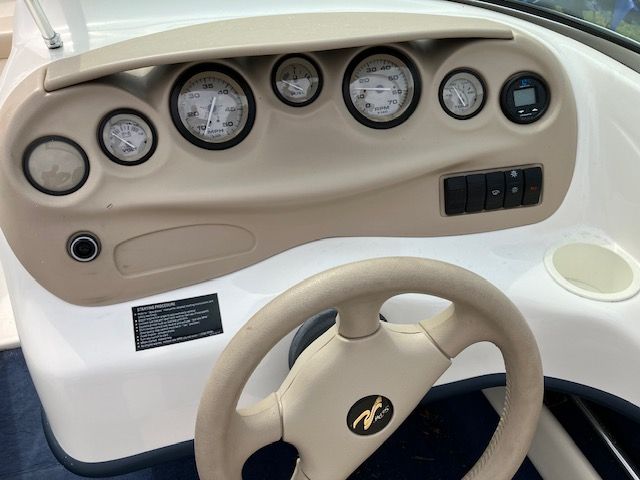 A boat dashboard with a steering wheel and various gauges