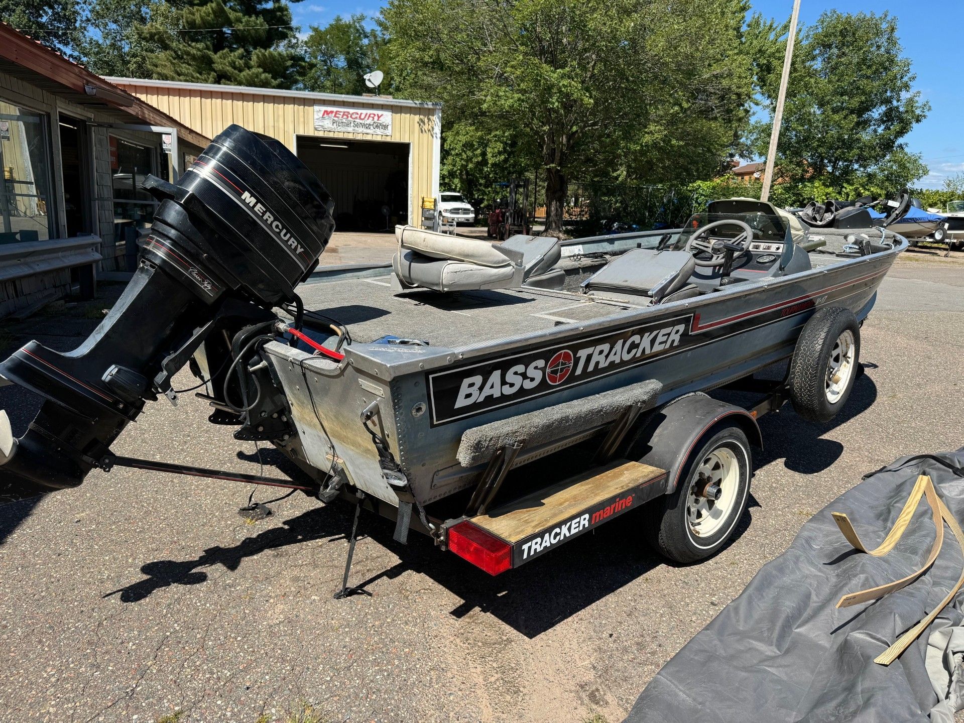 A bass tracker boat is parked on a trailer in a parking lot.