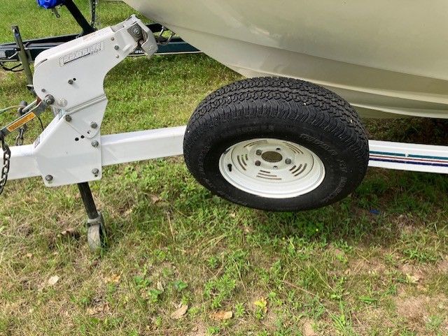 A boat is sitting on a trailer in the grass.