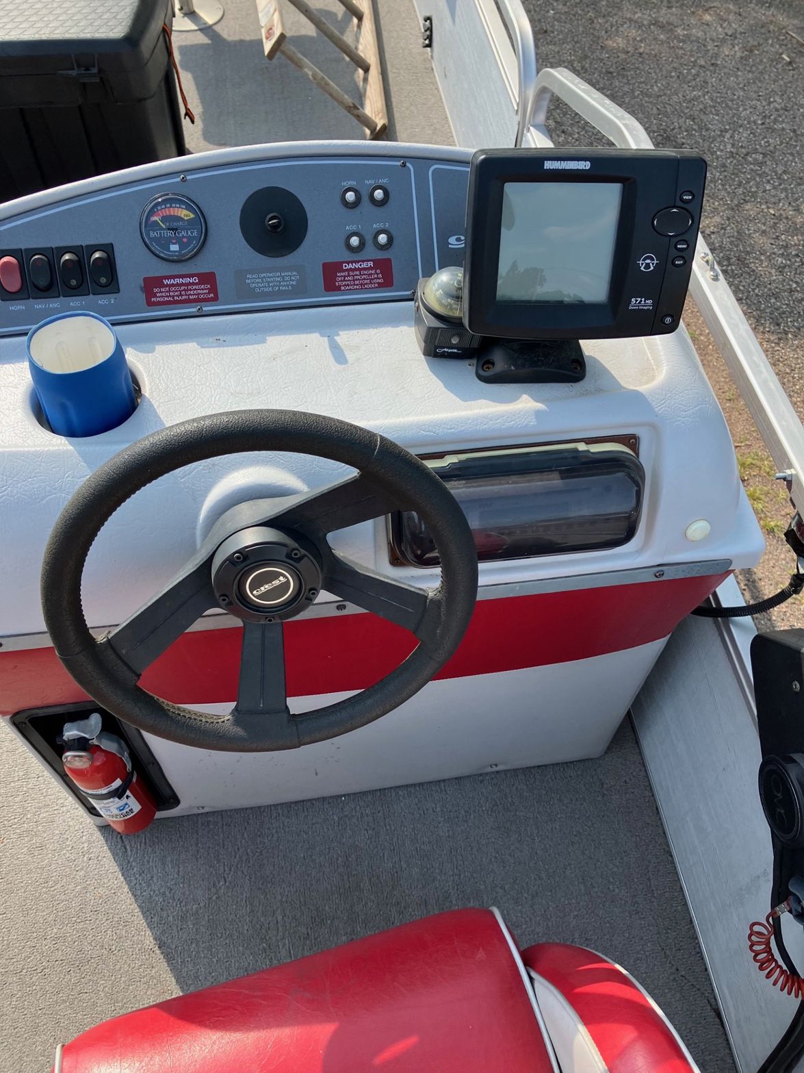 Boat's helm, with a steering wheel, gauges, fish finder, and control panel. Red and gray accents are visible.