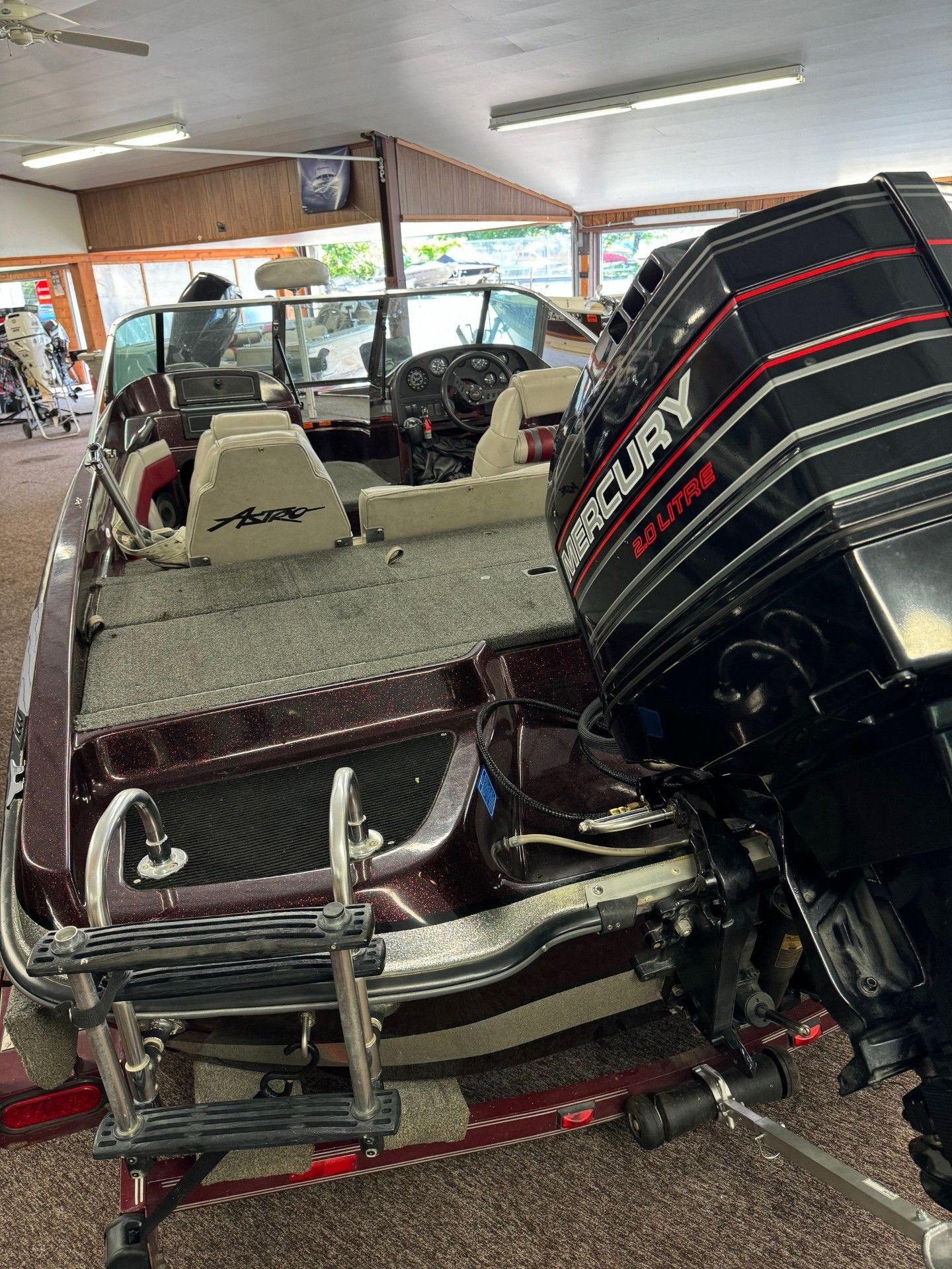 A boat with a mercury outboard motor is parked in a room