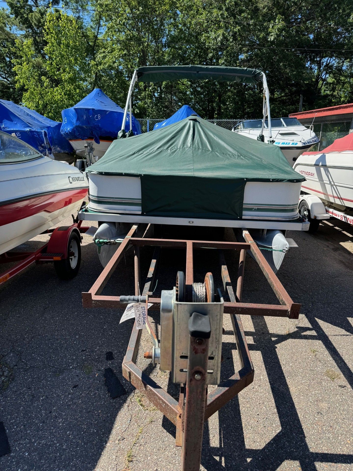 A pontoon boat is sitting on a trailer in a parking lot