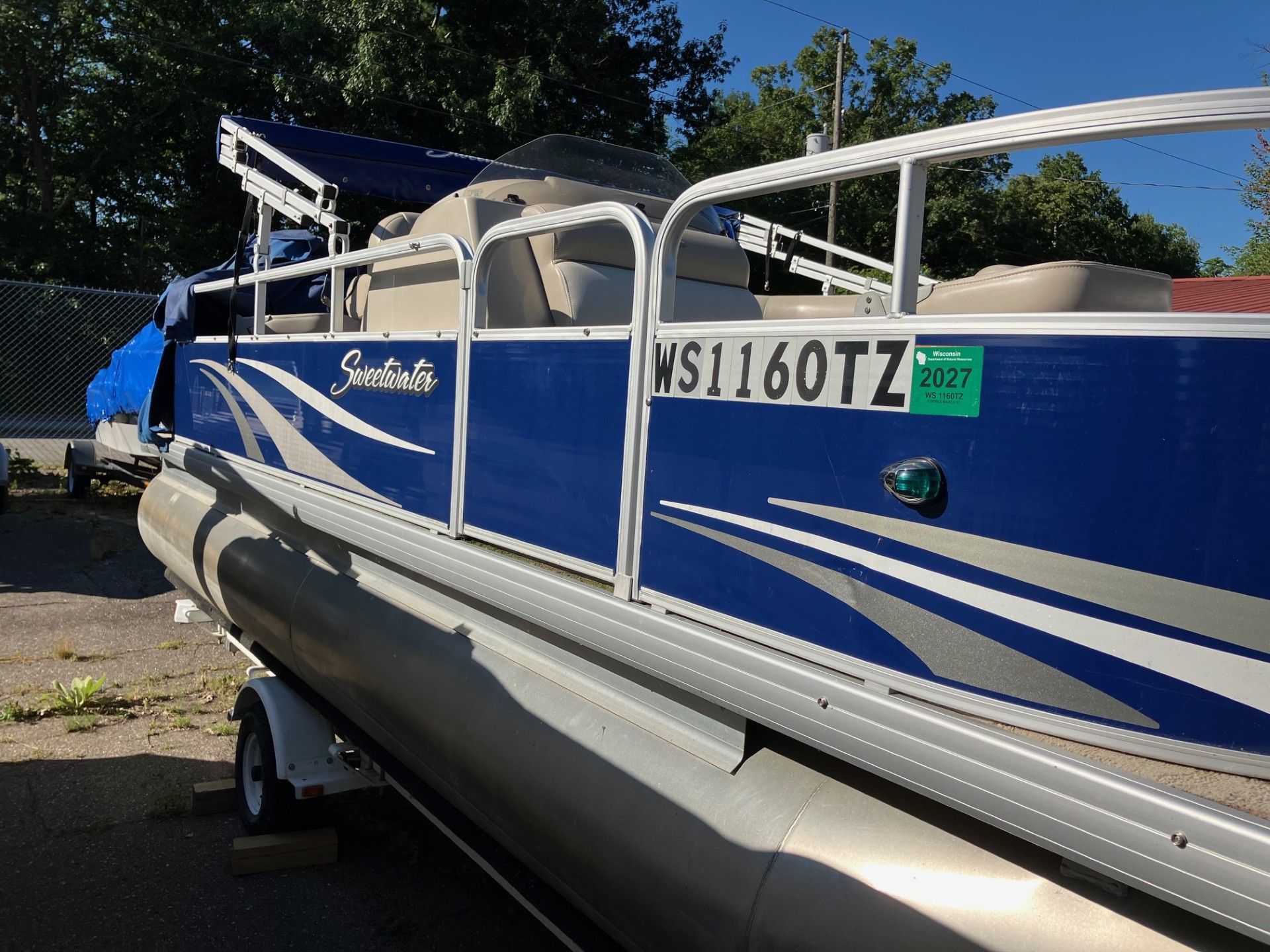 Blue and silver pontoon boat on a trailer; license plate NS1160TZ.