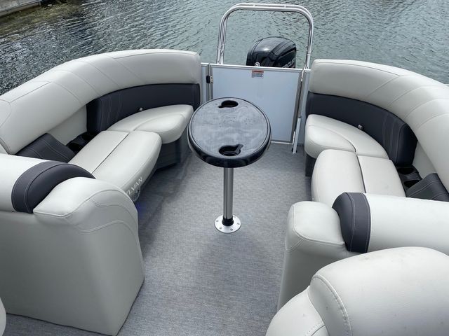 The inside of a pontoon boat with a table and chairs