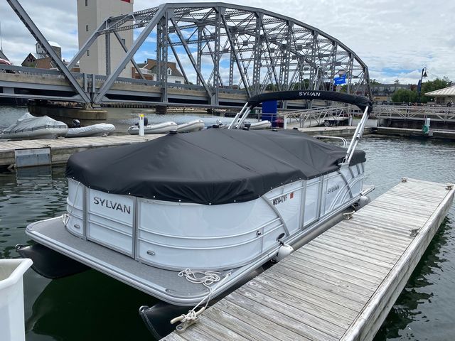 A pontoon boat is docked at a dock under a bridge