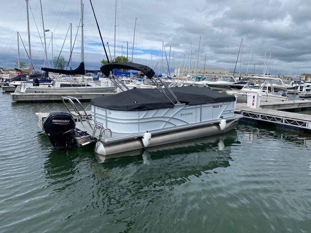 A pontoon boat is docked in a marina next to a dock