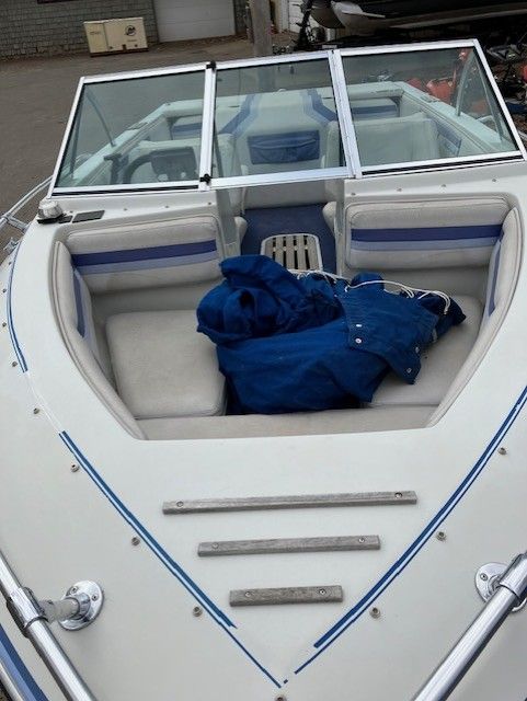 A white boat with a blue cover on the back seat