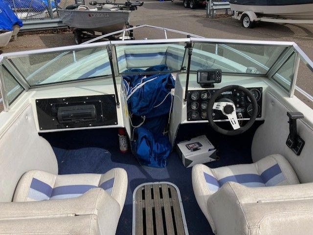The inside of a boat with a steering wheel and seats