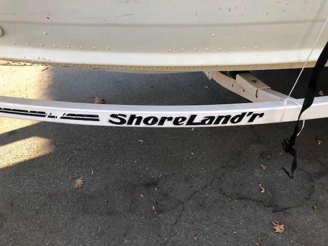 A Shoreland trailer is attached to a white car